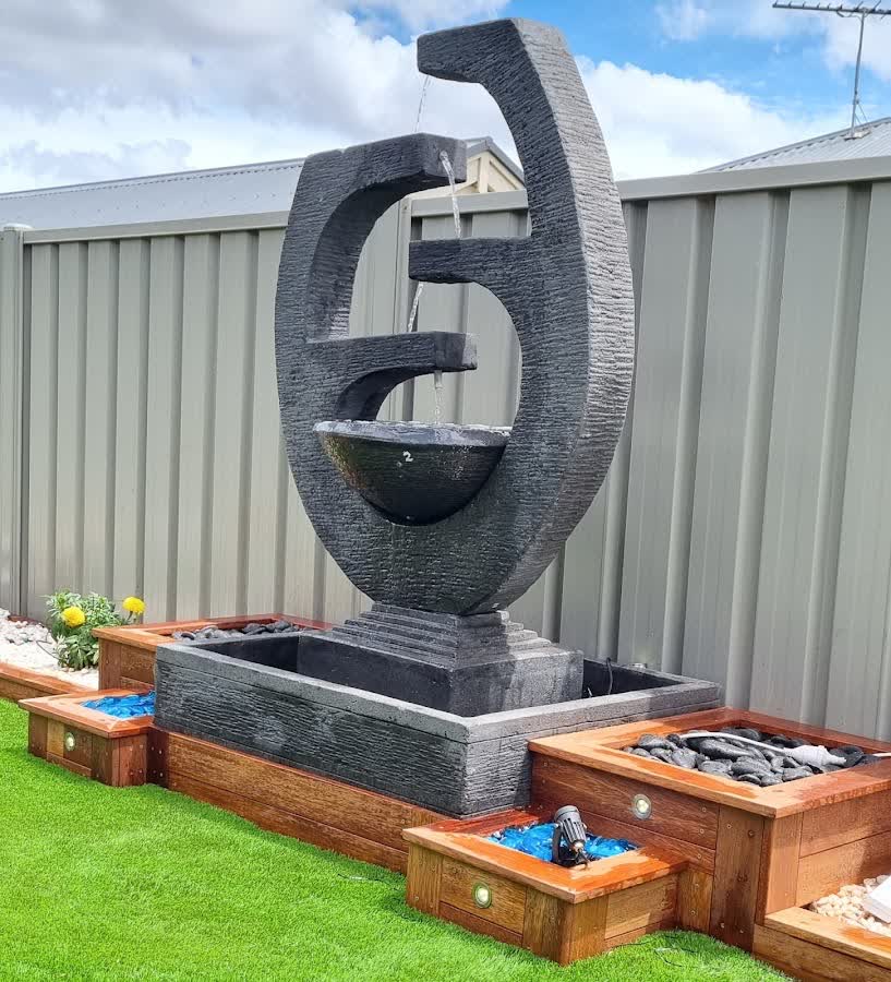 Sleek spiral concrete water feature on turf with timber planter boxes