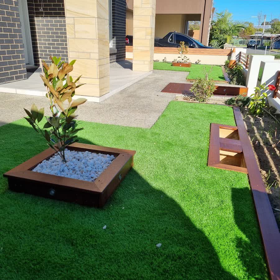 Modern front yard with artificial turf, a timber tree planter and pebble inlay