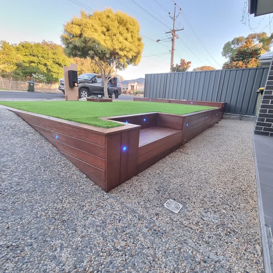 Sunken timber bench seating built into a raised turf platform with LED lighting