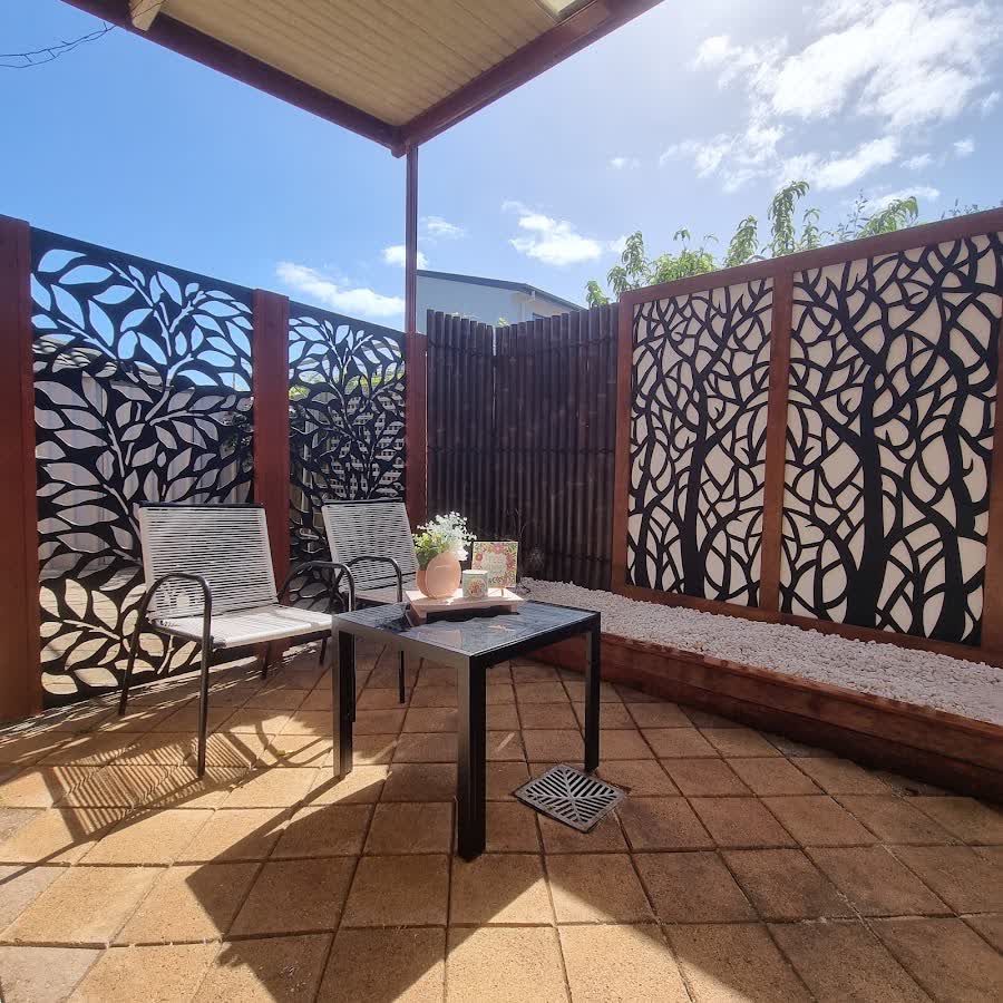 Courtyard patio with decorative tree-pattern privacy screens and outdoor seating